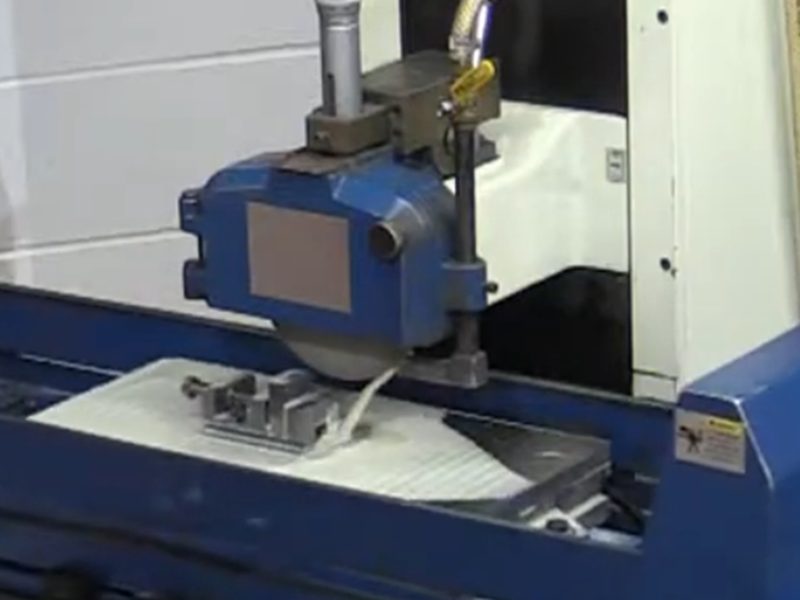 A surface grinder with a part held on the magnetic chuck under the
                      wheel and coolant feeding the cut, operated from the table handwheels
                      at the front.