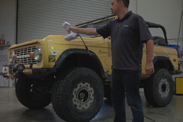 A technician sweeps a handheld 3D scanner along the front wing of a
                      classic Ford Bronco in a workshop, capturing the panel shape for
                      reverse engineering.